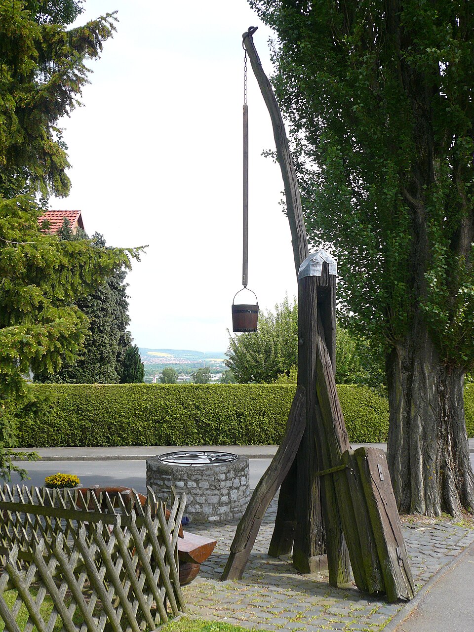 Der Klotzbrunnen in Hetjershausen – steinerner Rundbrunnen mit hölzernem Förder­gestell auf dem Dorfanger
